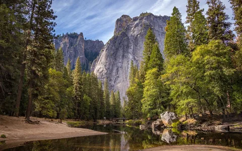 Granite cliffs and pine forest reflected in a calm river