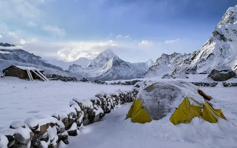 Snow-covered base camp tent below Himalayan peaks