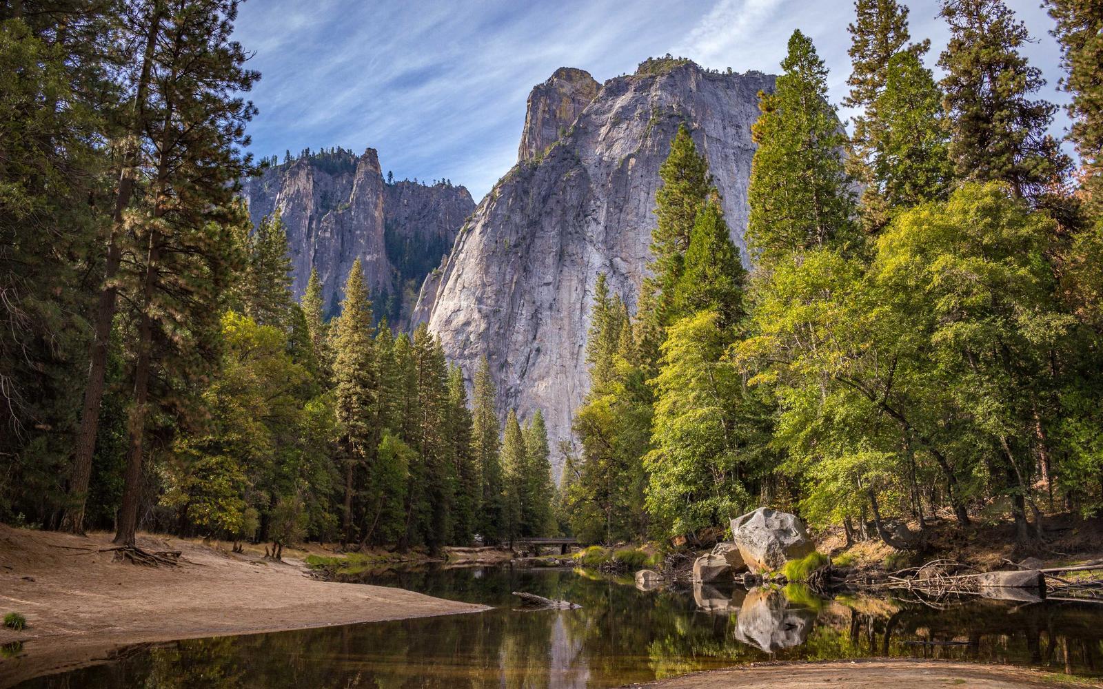 Granite cliffs and pine forest reflected in a calm river